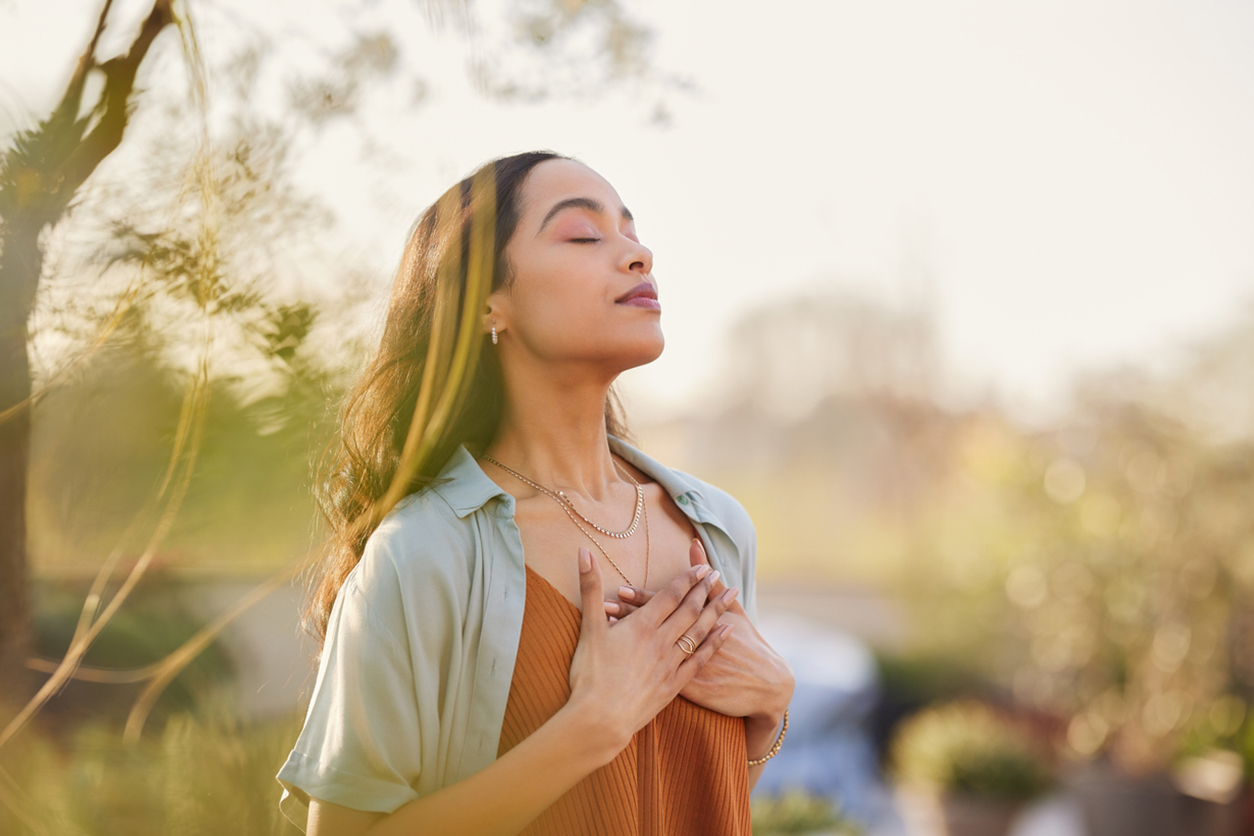 Une femme métisse se détend et respire de l’air frais à l’extérieur au coucher du soleil